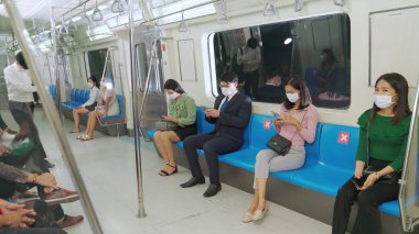 Kalabalık bir metroda maske takan insanlar.