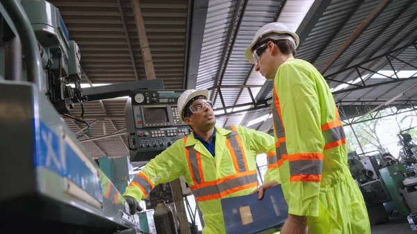 Group of factory workers using machine equipment in factory workshop