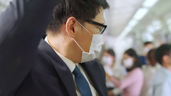 Hombre joven con máscara facial viaja en tren de metro lleno de gente —  Fotos de Stock