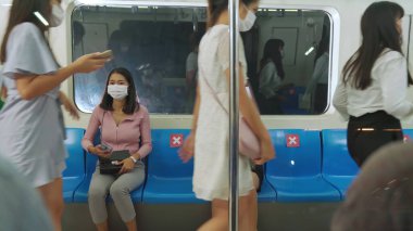 Kalabalık bir metroda maske takan insanlar.