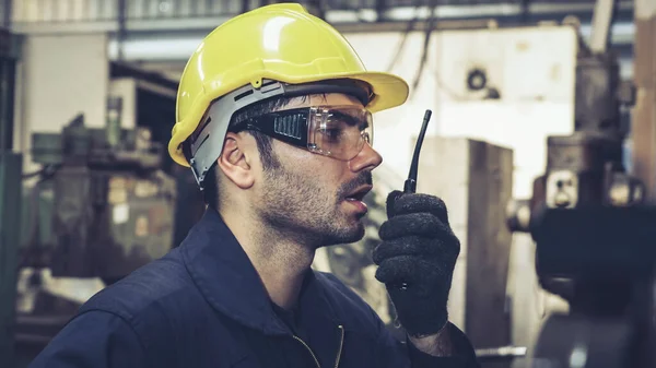 Operaio che parla alla radio portatile mentre ispeziona le parti di macchine — Foto Stock