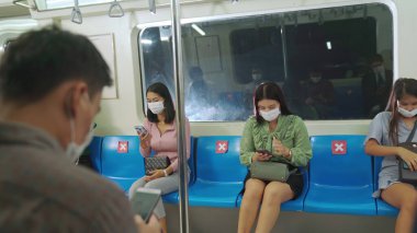 Kalabalık bir metroda maske takan insanlar.
