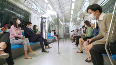 Kalabalık bir metroda maske takan insanlar.