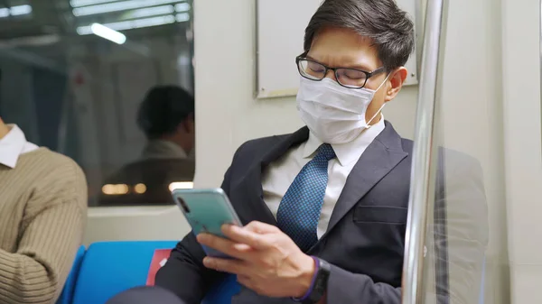 Reisender trägt Gesichtsmaske bei Handynutzung in S-Bahn — Stockfoto