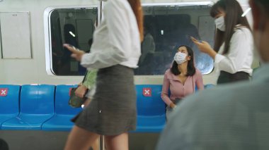 Kalabalık bir metroda maske takan insanlar.