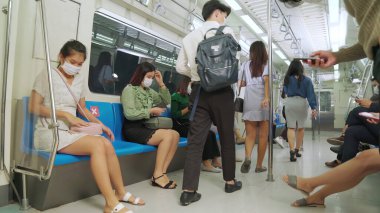 Kalabalık bir metroda maske takan insanlar.
