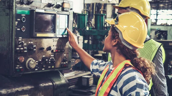 Group of factory workers using machine equipment in factory workshop