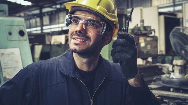 Trabalhador da fábrica falando em rádio portátil enquanto inspeciona peças de máquinas — Fotografia de Stock