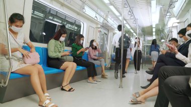 Kalabalık bir metroda maske takan insanlar.