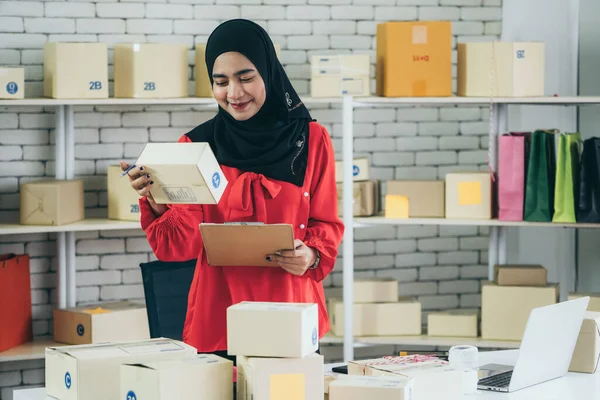 Musulmán vendedor en línea en casa oficina con caja de envío para la entrega al cliente. — Foto de Stock