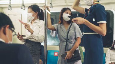 Kalabalık bir metroda maske takan insanlar.