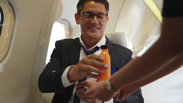 Empresário tem suco de laranja servido por uma aeromoça em avião — Fotografia de Stock