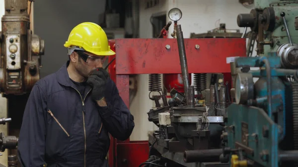 Fabrika işçisi, makine parçalarını incelerken taşınabilir radyodan konuşuyor. — Stok fotoğraf