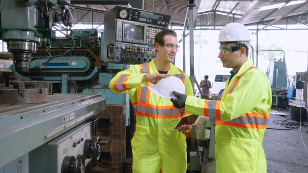Factory worker warn coworker about safety and give hardhat to him