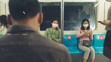 Kalabalık bir metroda maske takan insanlar.