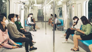 Kalabalık bir metroda maske takan insanlar.