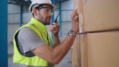 Profesyonel kargo işçisi başka bir işçiyle bağlantı kurmak için telsizle konuşuyor.