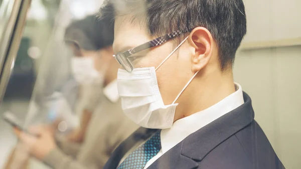 Junger Mann mit Gesichtsmaske fährt in überfüllter U-Bahn — Stockfoto