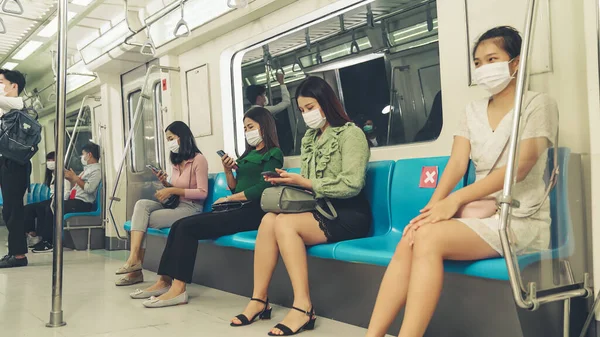 Kalabalık bir metroda maske takan insanlar.