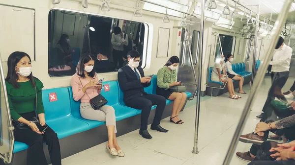 Kalabalık bir metroda maske takan insanlar.