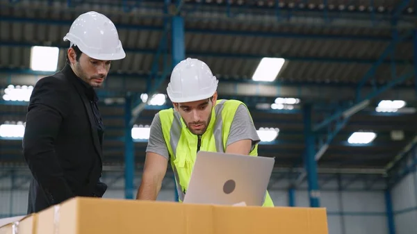 Two factory workers working and discussing manufacturing plan in the factory .