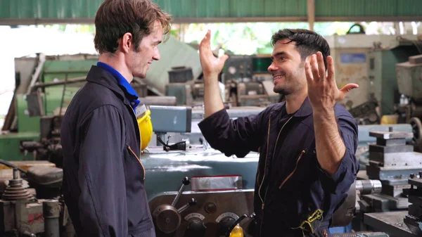 Tired factory workers taking a break and talking to coworker in the factory