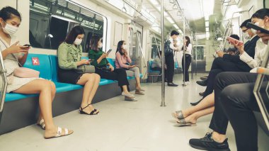 Kalabalık bir metroda maske takan insanlar.