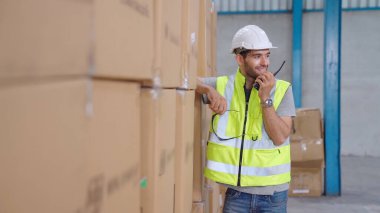 Profesyonel kargo işçisi başka bir işçiyle bağlantı kurmak için telsizle konuşuyor.