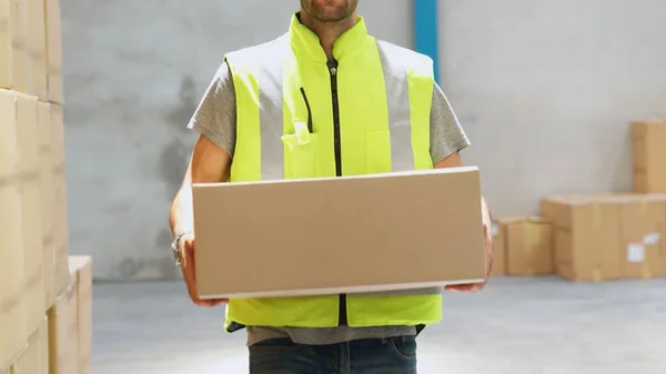 Trabalhador do armazém transportando caixa de papelão no armazém — Fotografia de Stock