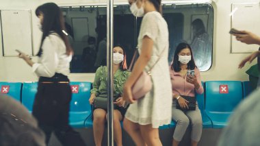 Kalabalık bir metroda maske takan insanlar.