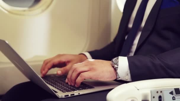 Genç işadamı uçakta dizüstü bilgisayar kullanıyor. — Stok video