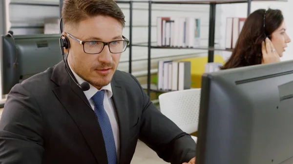Επιχειρηματίες που φορούν ακουστικά και εργάζονται στο γραφείο — Φωτογραφία Αρχείου
