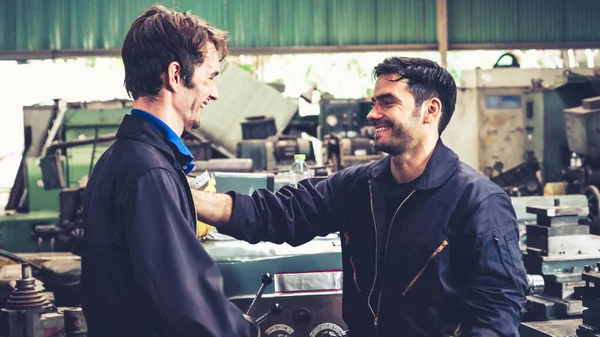 Tired factory workers taking a break and talking to coworker in the factory