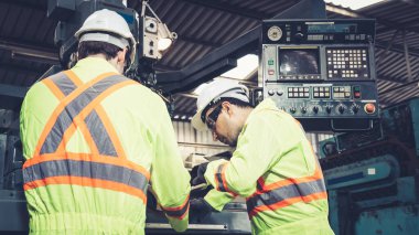 Fabrika atölyesinde makine ekipmanı kullanan bir grup işçi.