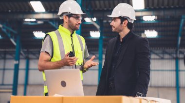 Fabrikada çalışan ve üretim planını tartışan iki fabrika işçisi. .