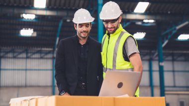 Fabrikada çalışan ve üretim planını tartışan iki fabrika işçisi. .