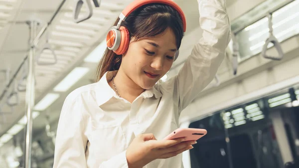 Młoda kobieta korzystająca z telefonu komórkowego w pociągu publicznym — Zdjęcie stockowe
