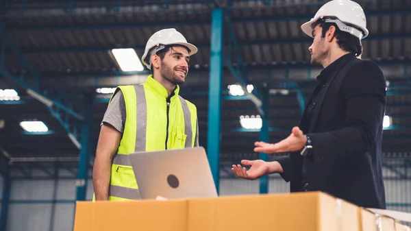 Two factory workers working and discussing manufacturing plan in the factory .