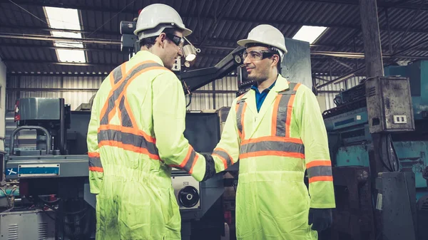 Factory workers handshake with team member in the factory