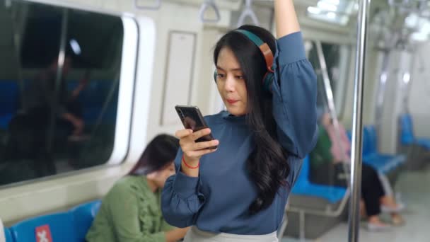Молодая женщина, использующая мобильный телефон в общественном поезде — стоковое видео