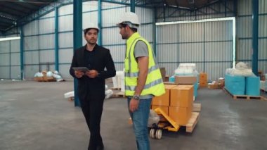 Fabrika işçileri depodaki bir yük arabasında kutu teslimatı yapıyor. .