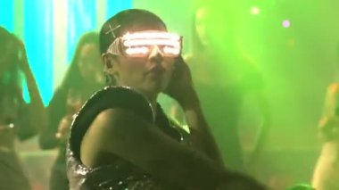 Bir grup insan disko gece kulübünde DJ 'in sahnede çaldığı müzikle dans ediyor.
