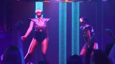 Bir grup insan disko gece kulübünde DJ 'in sahnede çaldığı müzikle dans ediyor.