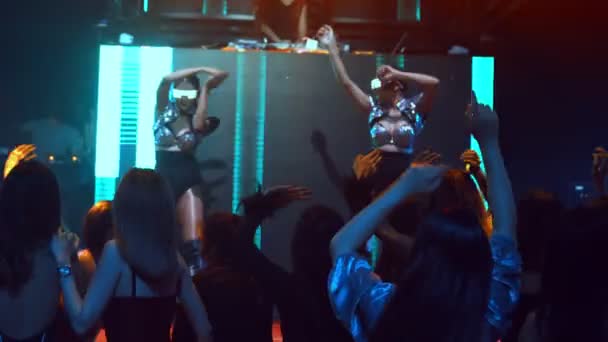 Grupo de personas bailan en discoteca al ritmo de la música de DJ en el escenario — Vídeos de Stock