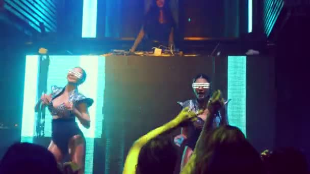 Grupo de personas bailan en discoteca al ritmo de la música de DJ en el escenario — Vídeos de Stock