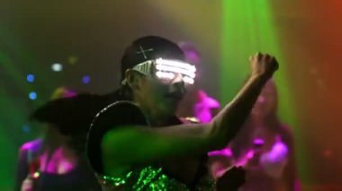Bir grup insan disko gece kulübünde DJ 'in sahnede çaldığı müzikle dans ediyor.