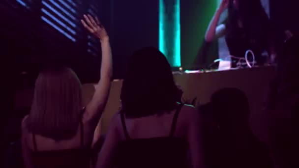 Groep mensen dansen in disco nachtclub op de beat van muziek van DJ op het podium — Stockvideo