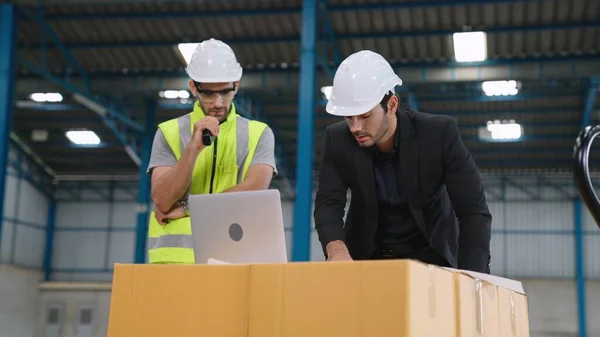 Two factory workers working and discussing manufacturing plan in the factory .