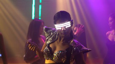 Bir grup insan disko gece kulübünde DJ 'in sahnede çaldığı müzikle dans ediyor.