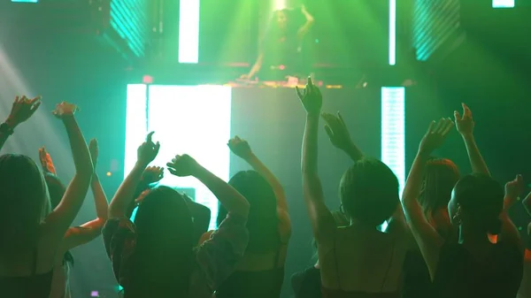 Group of people dance in disco night club to the beat of music from DJ on stage — Stock Photo, Image